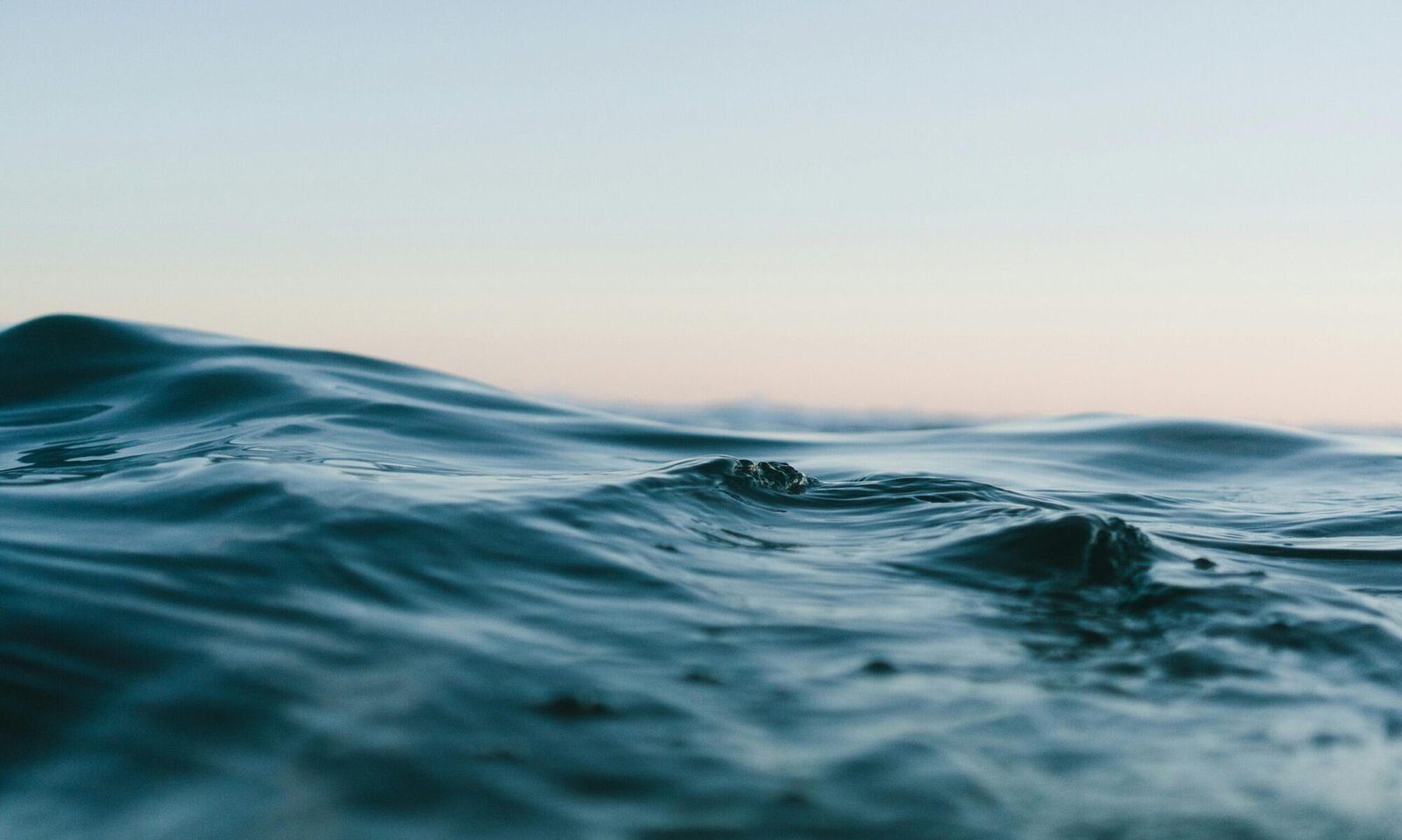 Tranquil ocean waves under a soft sunset sky, perfect for backgrounds.